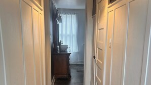 A hallway with wooden flooring, white walls, and a door leading to a bathroom.