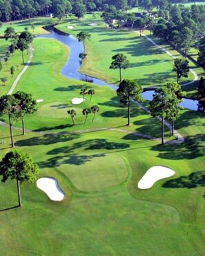 Ein Golfplatz mit Sandbunkern, Wasserhindernissen und Bäumen.