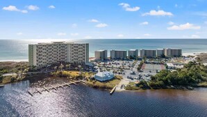 Un hotel sulla costa con diversi edifici, un parcheggio e vista sul lungomare.