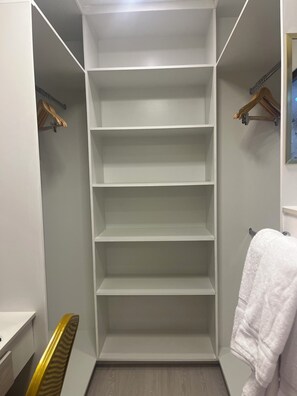 A walk-in closet with multiple shelves, a wooden chair, and a hanging rack. - Modern, Cozy and Stylish. (Diego Martin)