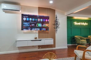 Ein modernes Wohnzimmer mit einem an der Wand befestigten Flachbildfernseher, einem weißen Konsolentisch und einer grünen Akzentwand.