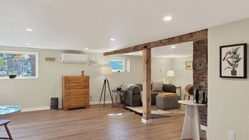 Une pièce spacieuse avec un plancher en bois, une commode en bois, une table ronde et un canapé.