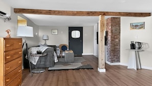 Una sala de estar moderna con un sofá, una mesa de centro, un aparador de madera y una puerta que da a otra habitación.
