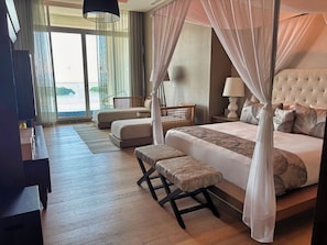 A hotel room with a large bed, a sitting area, a desk, and a view of the outdoors. - Spacious 4-Bedroom Grand Luxxe Retreat, Perfect for Families and Groups (Nuevo Vallarta)