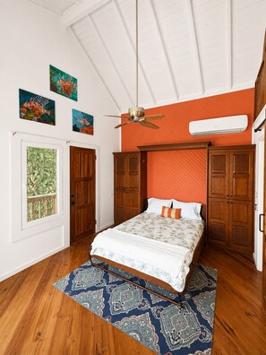 Ein Schlafzimmer mit Bett, Holzschrank, Deckenventilator und einem Kunstwerk an der Wand.