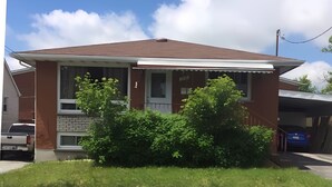 Uma casa de dois andares com fachada de tijolos, varanda frontal e garagem.