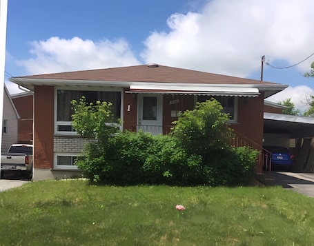 A two-story house with a brick facade, a front porch, and a garage.. Basement Queen Bedroom-C(Private Room,Shared Bathroom)