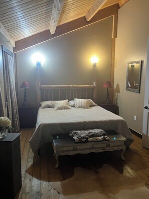 A bedroom with a wooden bed, two bedside lamps, a mirror, and a bedside table with a lamp. - Superb 5 -bedroom Estate in Monroe perfect for family getaways (Monroe)
