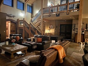 A spacious living area with a pool table, leather sofas, a staircase, and a dog. - Superb 5 -bedroom Estate in Monroe perfect for family getaways (Monroe)