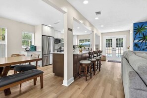 Cozinha moderna com ilha central, mesa de jantar de madeira e banquetas de bar.
