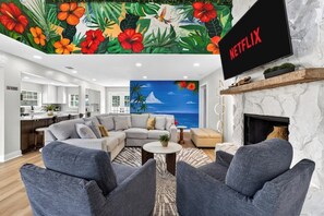 A living room with a sofa, armchairs, a TV, and a fireplace.