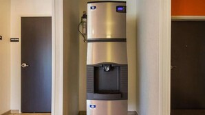A stainless steel water dispenser in a hallway with a door on the left and a wall on the right. - Days Inn by Wyndham South Bend /notre Dame (South Bend)