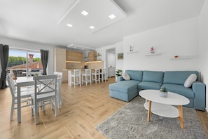 A modern living room with a sofa, a dining table with chairs, a kitchen area, and a balcony with a view. - Villa LanaB – Private Pool and Great Location by Istrabook (Labin)