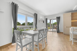 A modern kitchen with white cabinetry, a dining area with a white table and chairs, and a view of the outdoors. - Villa LanaB – Private Pool and Great Location by Istrabook (Labin)
