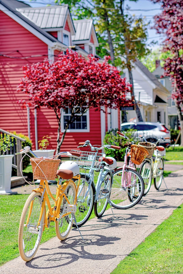 Bicycles parked on a sidewalk with a red building in the background.