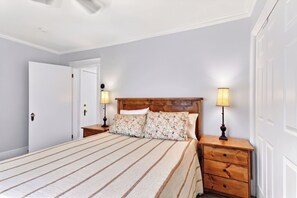 Un dormitorio con una cama, dos mesitas de noche, un cabecero de madera y dos lámparas.