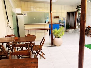 L’intérieur d’un restaurant avec des tables et des chaises en bois, une grande plante en pot et un comptoir bleu.