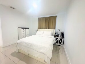 Ein Schlafzimmer mit einem Bett, einem Nachttisch, einer Kommode und einem Spiegel.