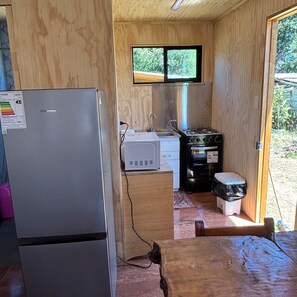 Eine kleine Küche mit Kühlschrank, Herd, Spüle und einem Fenster.