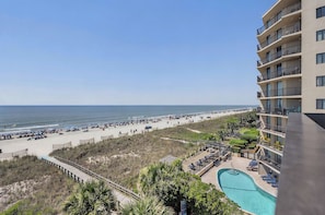 A beach view from a hotel balcony, a swimming pool, and a beach with umbrellas and sun loungers. - Oceanfront Corner Unit-3BR Retreat at Waterpointe I (North Myrtle Beach)