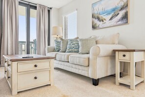 A living room with a sofa, a coffee table, a lamp, and a painting on the wall. - Oceanfront Corner Unit-3BR Retreat at Waterpointe I (North Myrtle Beach)