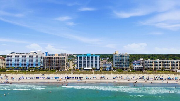 Ein Strandhotel mit mehreren Gebäuden, einem Sandstrand und Blick auf den Ozean.