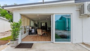 Ett modernt hus med en entré som består av en skjutdörr i glas, en liten uteplats och ett synligt garage.