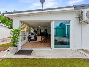 Ett modernt hus med en entré som består av en skjutdörr i glas, en liten uteplats och ett synligt garage.