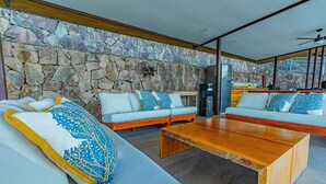 A modern living room with a stone wall, a wooden coffee table, and a sofa with patterned cushions.