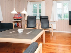 A dining area with a table, two chairs, a bookshelf, and a window with curtains. - 6 Person Holiday Home in Odder (Odder)