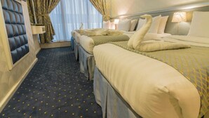 A hotel room with a large bed, two smaller beds, a padded headboard, a window with curtains, and a carpet with a pattern. - Montana Hotel Makkah (Makkah)