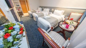 A hotel room with two beds, a sitting area with a chair and table, and a small balcony with a flower arrangement. - Montana Hotel Makkah (Makkah)