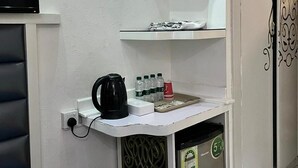 A small kitchenette area with a coffee maker, water bottles, and a trash bin. - Montana Hotel Makkah (Makkah)