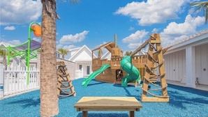 Un área de juegos infantiles con un tobogán, estructuras para escalar y un banco.