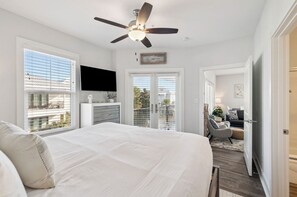 Ein Schlafzimmer mit einem großen Bett, einem Deckenventilator, einem Fernseher und einem Balkon mit Blick.