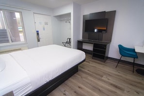 A bedroom with a bed, a TV, a desk, and a chair.