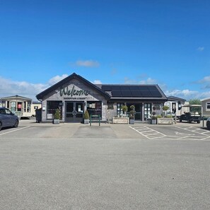 A building with a 'Welcome' sign, solar panels, and a parking lot.