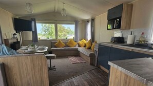 A modern kitchen with a dining area, a sofa with cushions, and a view of the outdoors.