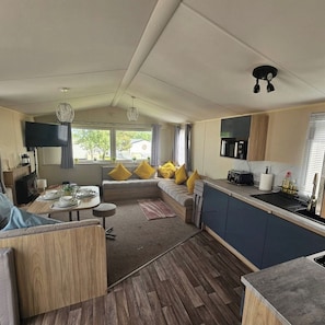 A modern kitchen with a built-in microwave, a dining area with a table set for two, and a cozy seating area with cushions.