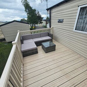A deck with a sofa and a table, a sign on the building, and a view of other similar buildings.