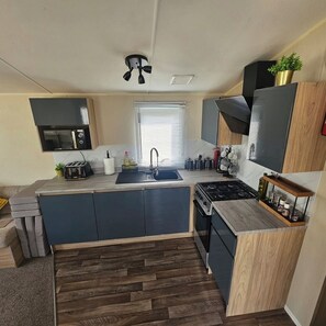 A compact kitchen with a central island, built-in microwave, and a gas stove.