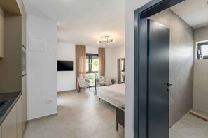 Ein modernes Hotelzimmer mit einem Bett, einem kleinen Esstisch und einem Fernseher.