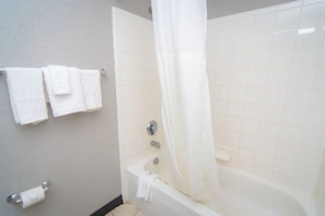 A bathroom with a bathtub, a shower curtain, and a towel rack with multiple towels.