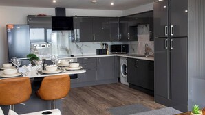 Une cuisine moderne avec des meubles gris, un four à micro-ondes encastré et un lave-linge.