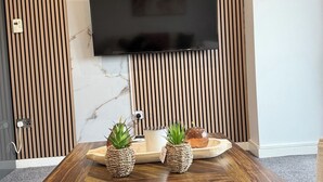 Un salon moderne avec une table basse en bois, un téléviseur à écran plat fixé au mur et un pare-feu en marbre.