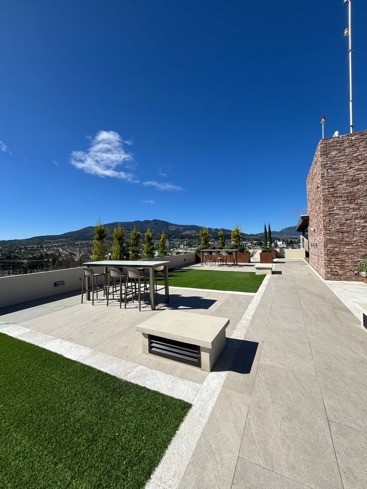 Una terrazza sul tetto con zona pranzo, un piccolo angolo relax e vista sulla città e sulle montagne.