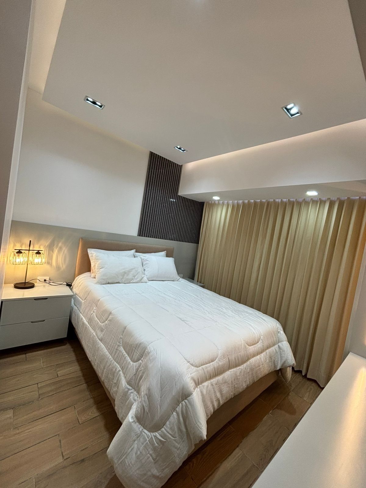 Una camera da letto moderna con un letto, un comodino e una abat-jour.