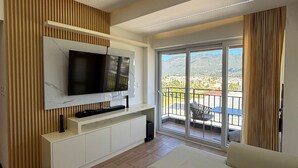 A modern living room with a flat-screen TV, a sofa, and a balcony with a view. - Apartamento moderno en Quetzaltenango (Quetzaltenango)