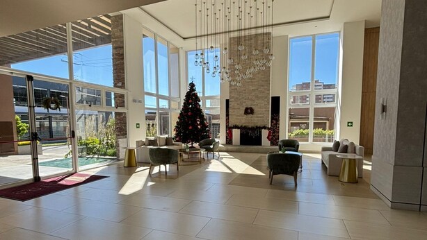 A spacious living area with a large window, a fireplace, and a Christmas tree. - Apartamento moderno en Quetzaltenango (Quetzaltenango)