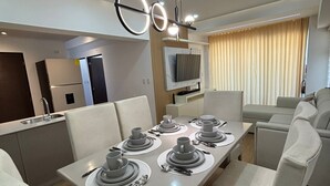 A modern dining area with a rectangular table set for four, surrounded by white chairs. - Apartamento moderno en Quetzaltenango (Quetzaltenango)